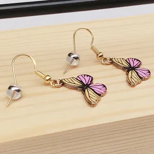 Close-up detail of colorful butterfly drop earrings with gold hooks and silicone earnuts