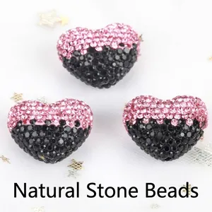 Macro detail of pink and black gradient rhinestone heart beads for DIY jewelry making.