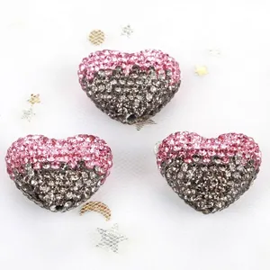 Macro view of pink and grey gradient heart-shaped rhinestone beads for DIY jewelry.