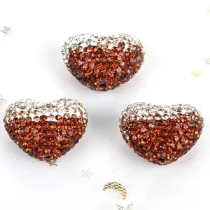 Macro view showing three heart-shaped gradient brown rhinestone Shamballa beads for DIY