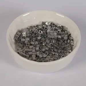 Détail macro de perles d'espacement carrées plaquées argent à tres lignes dans un bol