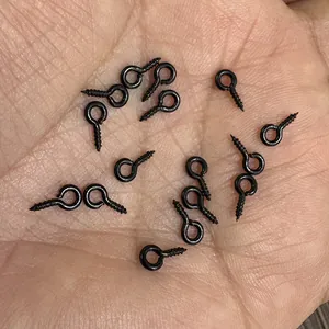 Macro view of small black metal eye pins for DIY jewelry making held in a person's palm