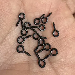 Small black screw eye hooks on a palm showing their tiny size for DIY jewelry crafts.