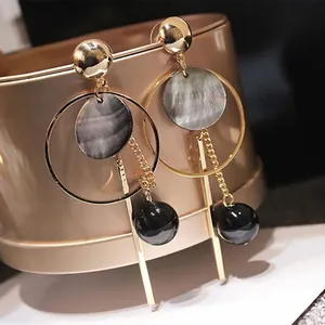 Nahaufnahme eleganter goldener Reifenohrringe mit grauen Marmorscheiben und Perlen