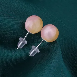 Nahaufnahme von DIY-Schüssel-Ohrsteckern mit rosa Farbverlaufperlen auf grüner Seide.