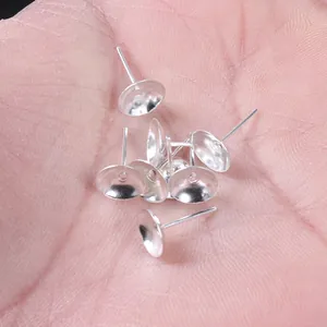 Vue macro de supports de boucles d'oreilles en forme de coupelle argentés dans une paume.