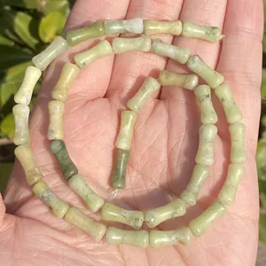 High resolution detail of natural light green bamboo shaped stone beads held in palm