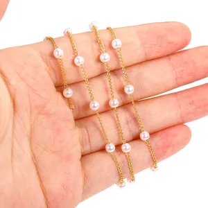Detailed macro view of an 18K gold-plated chain with delicate acrylic pearls in hand.
