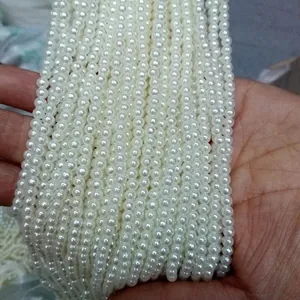 Close-up of multiple strands of white ABS imitation pearls for DIY jewelry making.
