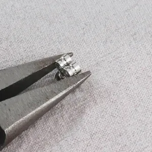 Detailansicht zum Festziehen versilberter Schmetterlings-Ohrringverschlüsse mit Zange.