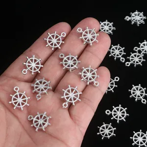 Detailed macro view of small silver ship wheel charms for DIY jewelry making projects