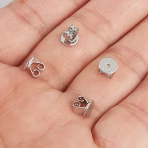 Makro-Detail von polierten S925 Sterlingsilber Schmetterlings-Ohrringrücken auf einer Hand