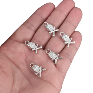 Silver skull and crossbones DIY jewelry pendants held in palm for clear size reference.