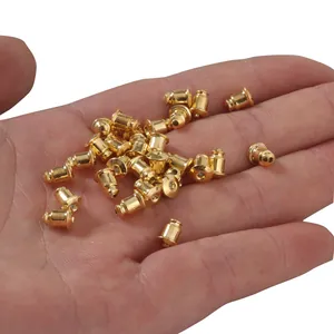 Nahaufnahme von goldenen Ohrring-Rückseiten aus Messing, gehalten in der Hand für DIY-Schmuck.