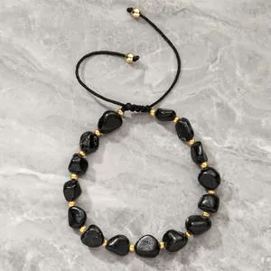 Close-up detail of an adjustable black tourmaline bead bracelet with gold spacers