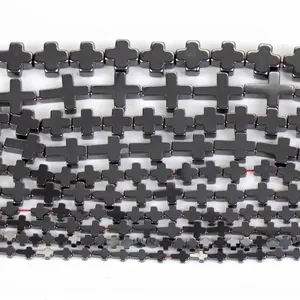 Close-up macro view of natural black hematite cross-shaped loose beads in multiple sizes