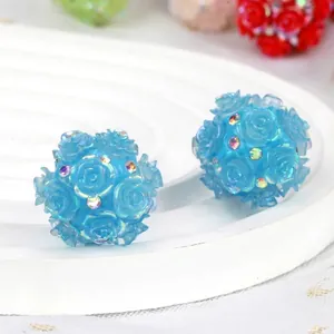 Close-up of blue camellia flower resin beads with satin finish and sparkling rhinestones