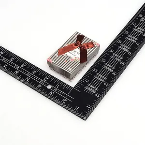 Detailed view of striped gift box with brown ribbon bow and ruler for scale measurements