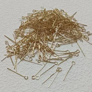 Close-up of golden metal eye pins for DIY jewelry making and beading projects.