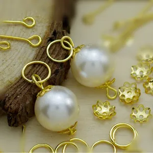 Detail view of DIY jewelry components including white pearls, gold bead caps, and rings.