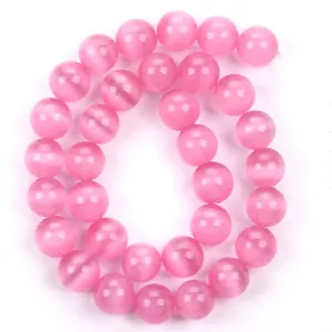 Primo piano di perline rotonde in pietra occhio di gatto rosa lucida per gioielli.