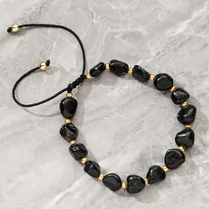 Close-up detail of adjustable black tourmaline bead bracelet with golden spacers