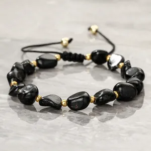 Close-up of black tourmaline stone bracelet with gold bead spacers and braided cord