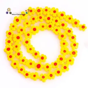 Macro detail of 8mm yellow plum flower glass beads with red centers for DIY jewelry