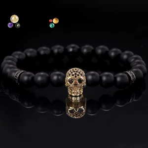 Macro detail of 8mm matte black beads and micro-pave gold skull charm on a trendy bracelet