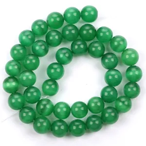 Macro dettaglio di vivaci perline in pietra occhio di gatto verde, perle tonde lucide per gioielli