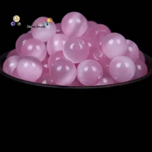 Perle tonde in vetro occhio di gatto rosa per gioielli fai da te, in una ciotola nera