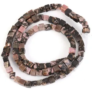 Nahaufnahme von 4mm Naturstein-Würfelperlen mit rosa-schwarzem Muster in Spiralform.