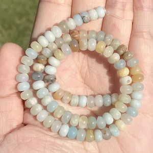 Detailed macro view of natural multicolor Amazonite rondelle stone beads held in palm