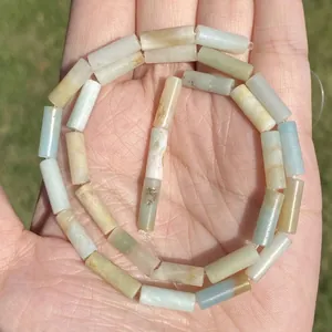 Close-up of cylindrical natural Amazonite stone beads with unique mineral textures.