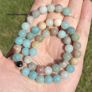 A detailed view of natural multi-colored Amazonite stone round beads held in palm