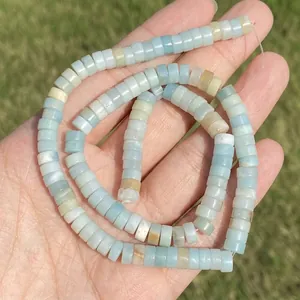 Close-up of natural light blue Amazonite disk-shaped beads held in hand.