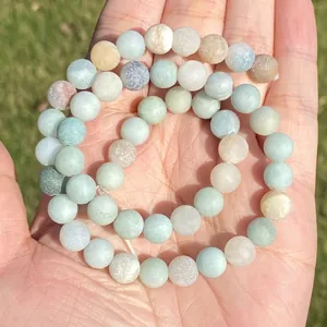 Detailed macro shot of natural Amazonite round stone beads with a matte finish on a palm.