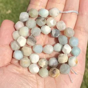 Close-up detail of faceted natural amazonite stone beads held in hand showing textures.