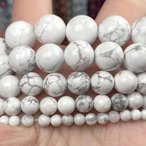Gros plan de perles d'howlite blanche naturelle marbrées de gris en tailles variées.