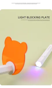 Detailed view of orange translucent light blocking plate on a handheld white nail lamp