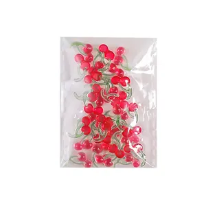 Set aus eisroten Kirsch-Nailart-Anhängern in einer durchsichtigen Plastiktüte