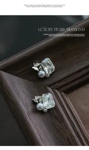 Macro view of luxury rectangular crystal and pearl nail art charms with silver butterfly.