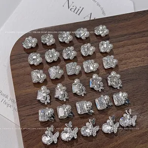Detailed view of assorted zircon and pearl nail art charms in butterfly and geometric shapes