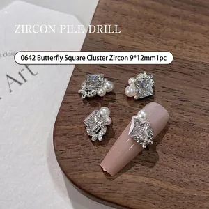 Macro detail showing silver butterfly nail charms with square zircon and white pearls.
