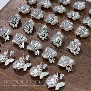 Macro view of sparkly zircon and pearl nail art charms arranged on a natural wooden base