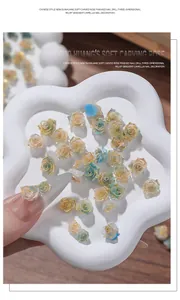 Detalle de dijes de rosas 3D para uñas con elegantes degradados y bordes dorados para manicura.