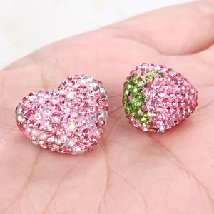 Vista macro di perline shamballa in strass rosa a forma di cuore e fragola per DIY
