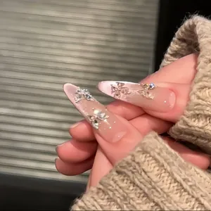 Close-up van amandelvormige nepnagels met sprankelende vlinder zircon strass decoratie.