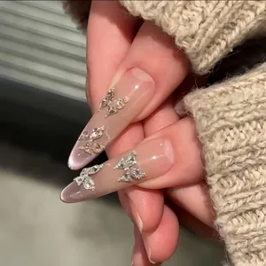 Close-up van fonkelende vlinder zirkonia steentjes op lange amandelvormige nagels