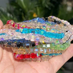 Hand holding a variety of vibrant multi-color 4mm square faceted crystal glass beads